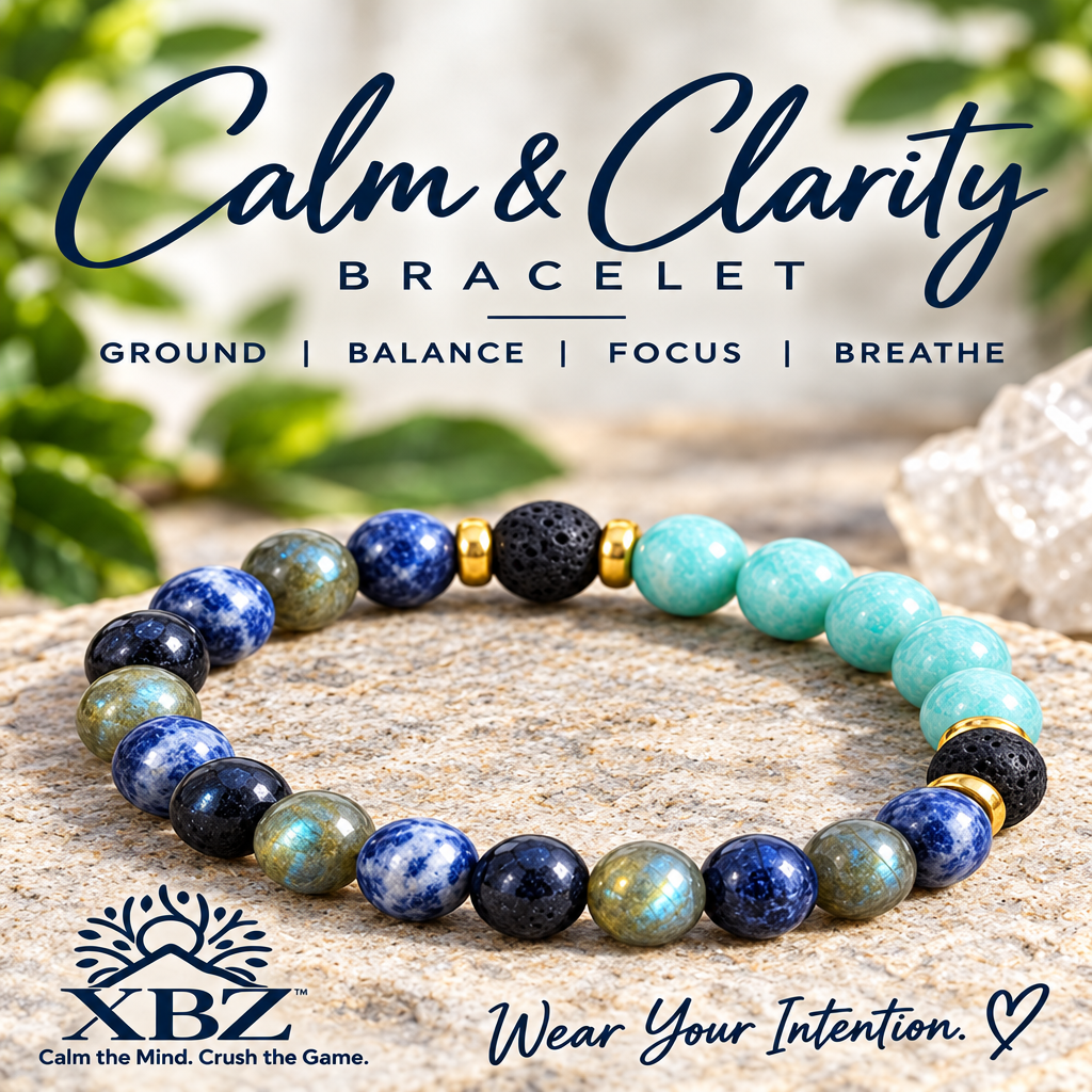 A beaded stretch bracelet labeled 'Calm & Clarity Bracelet' by XBZ, featuring round stones in navy, blue, black, mint green, gray, and gold spacer accents, displayed on a stone surface with a blurred natural background.