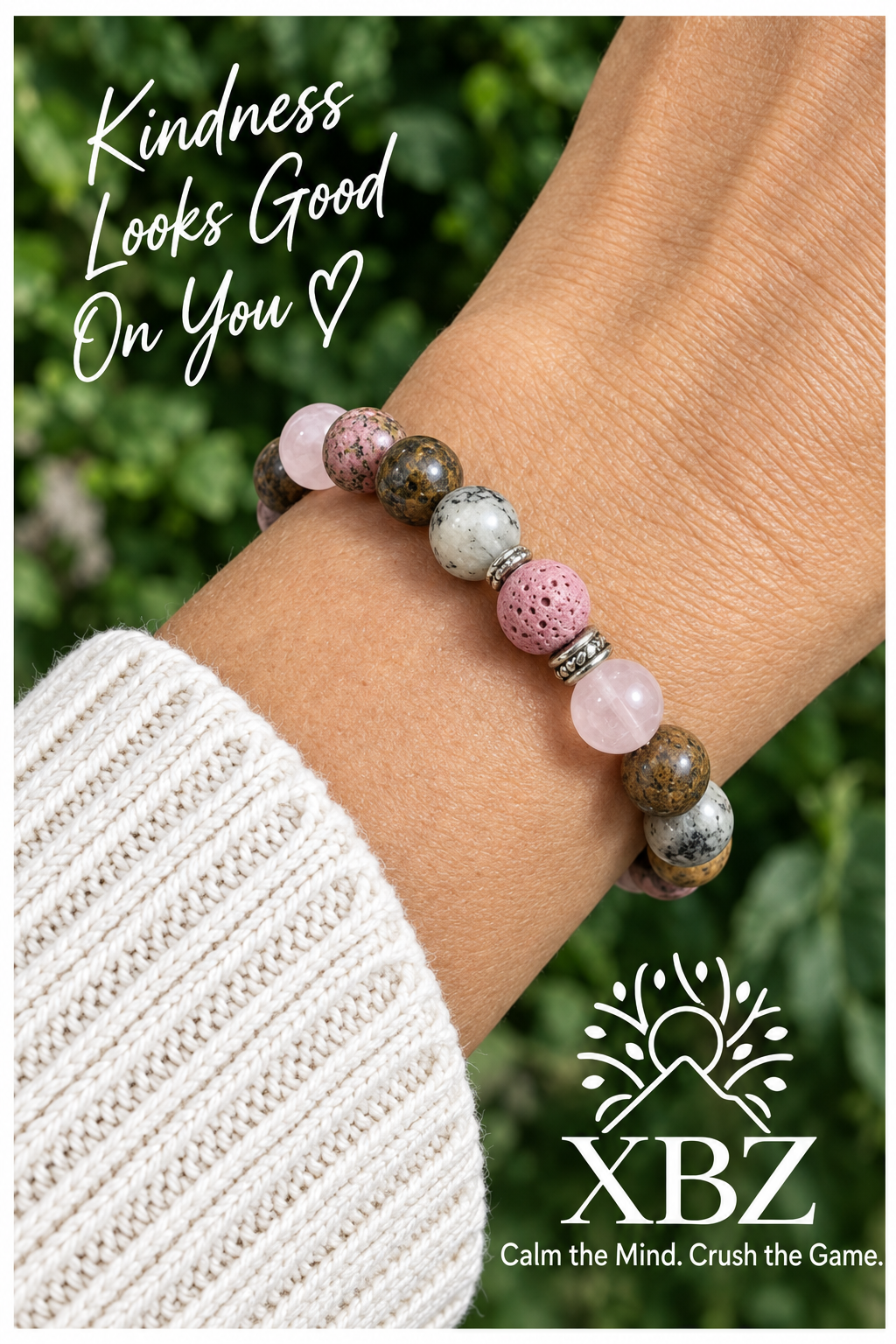 A beaded stretch bracelet worn on a person's wrist, featuring pink, speckled brown, and white beads with a small silver spacer. The image includes the text 'Kindness Looks Good On You' and the brand logo 'XBZ' at the bottom.