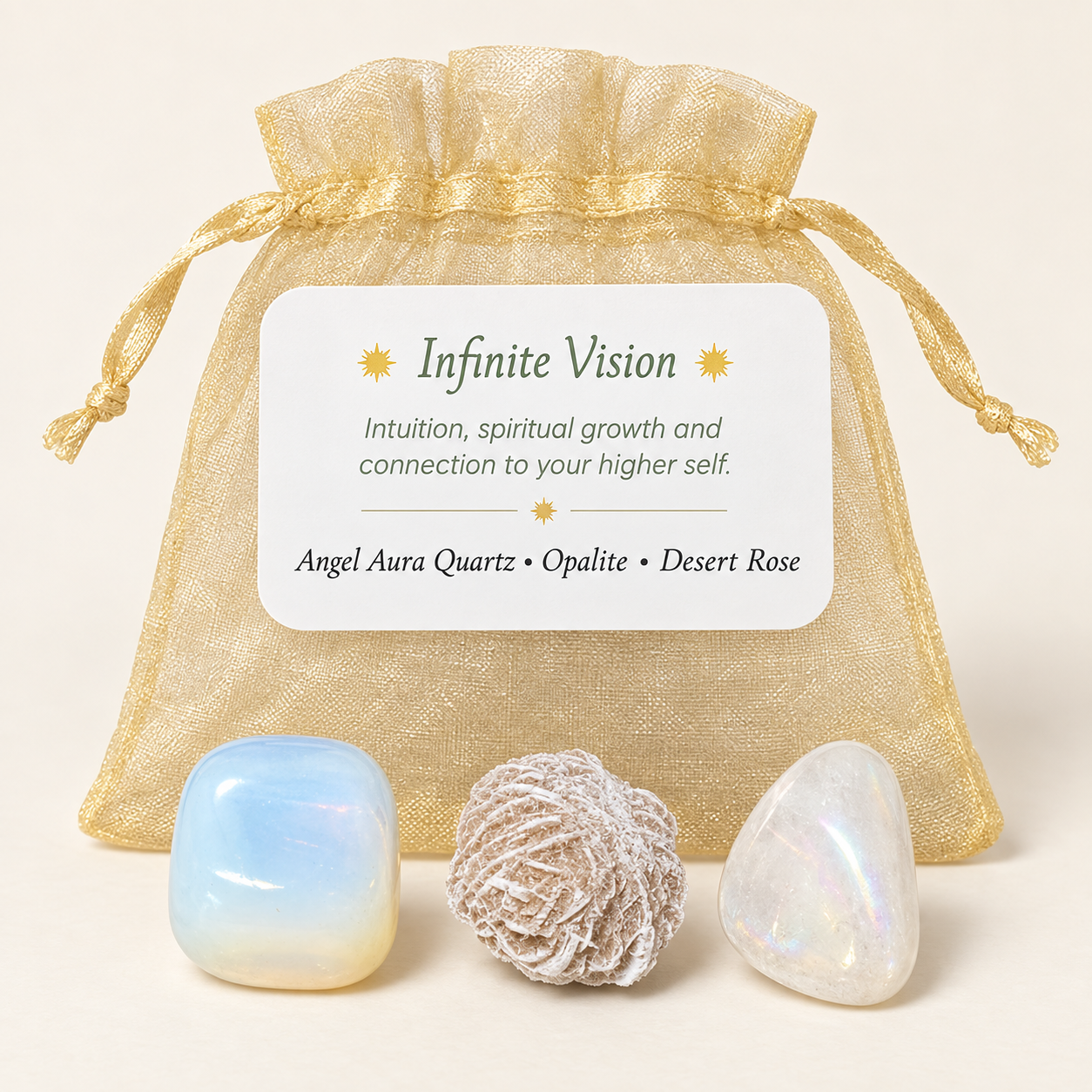 A gift set of three crystals in front of a gold sheer drawstring pouch with a printed label reading 'Infinite Vision' and listing Angel Aura Quartz, Opalite, and Desert Rose. The crystals are iridescent and textured, displayed on a warm cream background.