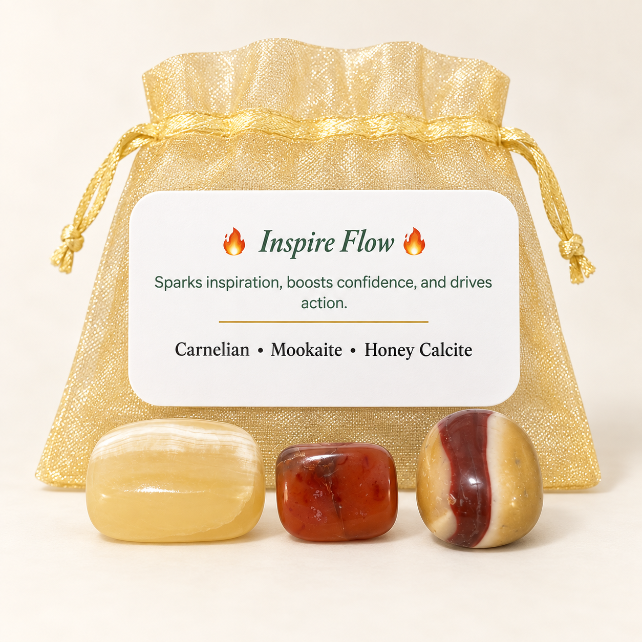 A set of three polished tumbled stones in front of a gold mesh drawstring pouch with a white label reading 'Inspire Flow' and listing Carnelian, Mookaite, and Honey Calcite.