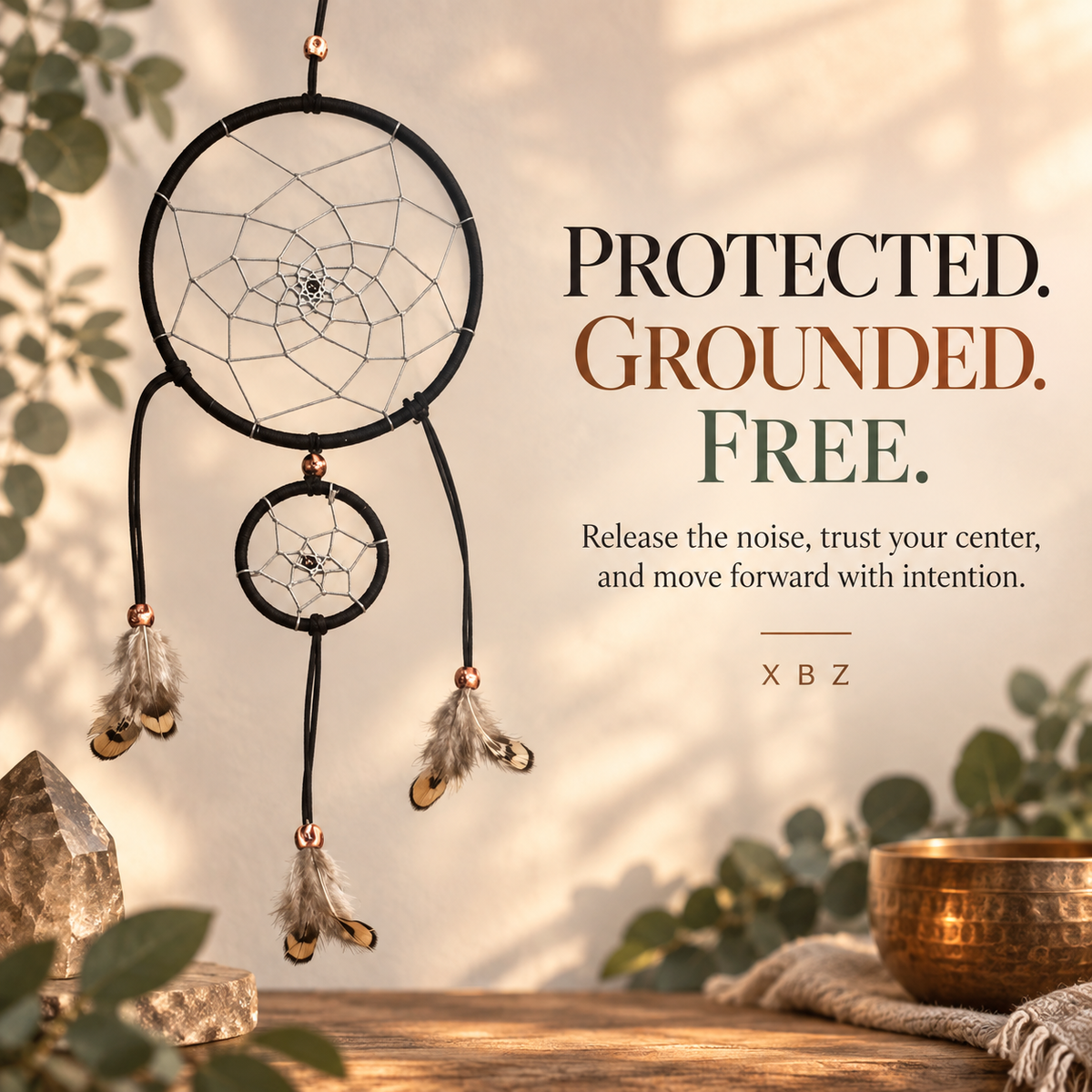 A black circular dreamcatcher with a smaller hanging dreamcatcher, feathers, and small metallic bells, displayed against a warm beige background with decorative leaves, crystals, and a copper bowl. Text on the right reads: 'PROTECTED.