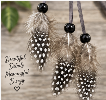 Three hanging feather ornaments with black beads and dark ribbons, shown against a blurred wood background with decorative text reading 'Beautiful Details Meaningful Energy'.